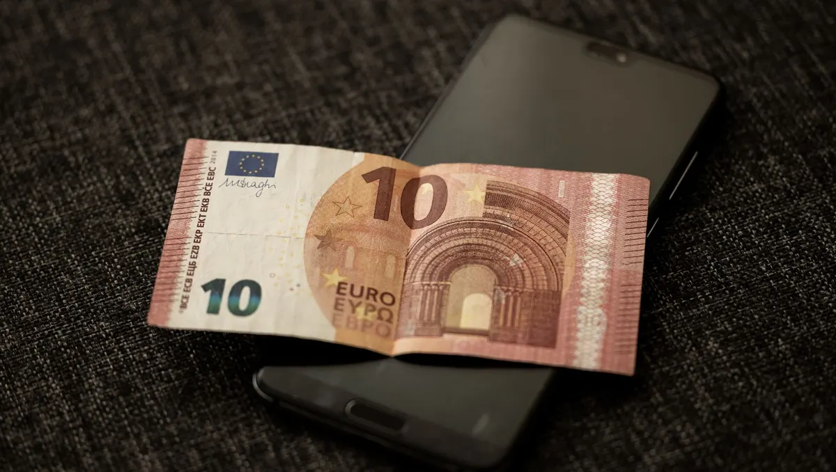 Ein Zehn-Euro-Schein liegt auf einem Smartphone auf dunklem Stoff